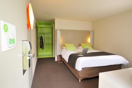 um quarto de hotel com uma cama com um computador portátil em Campanile Bourg-En-Bresse ~ Viriat em Viriat
