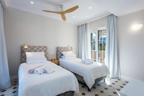 two beds in a white room with a window at Nancy Luxury Suites in Kassiopi