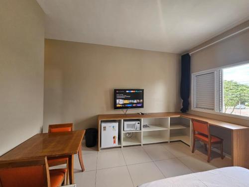 una habitación con un escritorio con televisión y una mesa en Suíte privativa próxima ao Sesc 1, en Bertioga