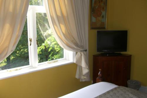 a bedroom with a bed and a window with a television at Ash Farm Country House in Little Bollington