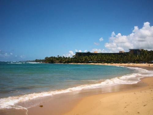 a sandy beach with the ocean and buildings in the background at Villa Kismet - Beachfront community with 3 pools in Brenas