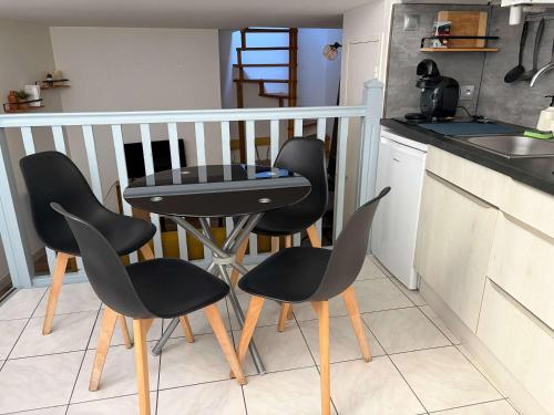 a kitchen with two black chairs and a table at Charmant T2 en duplex in Bordeaux