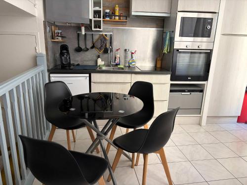a kitchen with black chairs and a table in it at Charmant T2 en duplex in Bordeaux