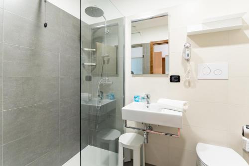 een witte badkamer met een wastafel en een douche bij Hotel Europa in Caorle