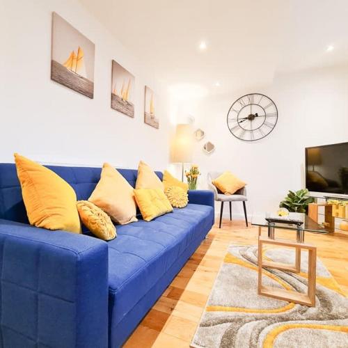 a blue couch with yellow pillows in a living room at Modern 4 bedroom flat near Brighton Station in Brighton & Hove