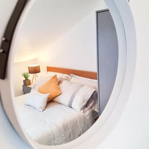 a mirror reflecting a bed with white sheets and pillows at Modern 4 bedroom flat near Brighton Station in Brighton & Hove