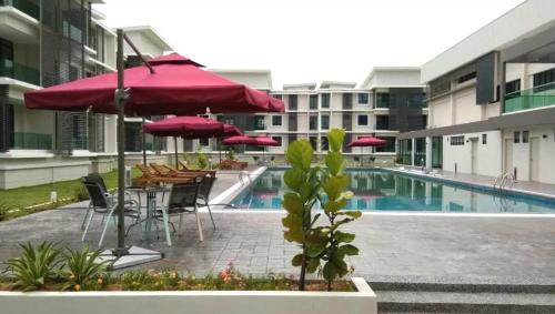 eine Terrasse mit Tischen und Sonnenschirmen und einem Pool in der Unterkunft A well-kept unit with four bedrooms and ensuite bathrooms in Kampar