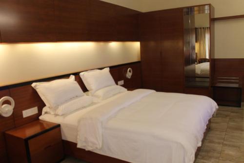 a bedroom with a large bed with white sheets and pillows at Hotel Moon Palace Kolwezi in Kolwezi