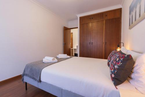 a bedroom with a large white bed and a wooden cabinet at Almada Noronha 37 in Almada