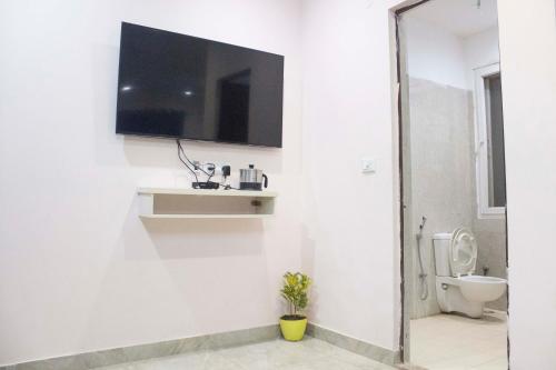 ein Bad mit WC und ein TV an der Wand in der Unterkunft JSB Hotel in Faridabad