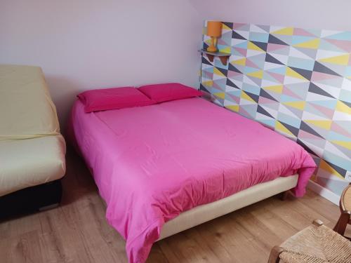 ein Schlafzimmer mit einem rosa Bett mit einer bunten Wand in der Unterkunft Lila in Souillé