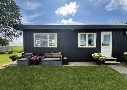 a black house with two couches in a yard at B&B bij de Roosjes in Blankenham