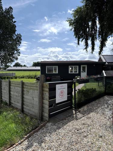 a black tiny house in a field with a fence at B&B bij de Roosjes in Blankenham
