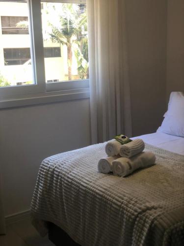 a bed with towels on it with a window at Baltico302 in Capão da Canoa