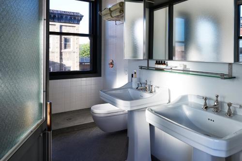 a bathroom with two sinks and a toilet and a window at The Robey, Chicago, a Member of Design Hotels in Chicago