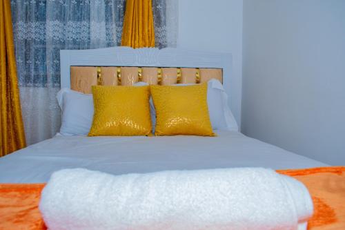 a bedroom with a white bed with yellow pillows at Delsy Stays in Ruaka