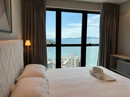 een hotelkamer met een bed en een groot raam bij Vista Mar - Suíte, Cozinha Completa, Até 4 pessoas in Itapema