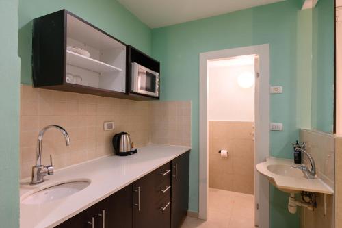 Un baño con dos lavabos y paredes verdes. en Marina Beach Hotel, en Tel Aviv