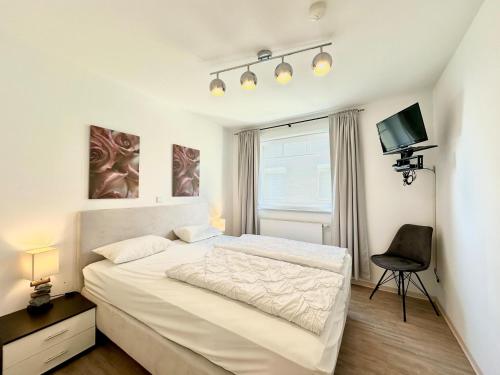 a bedroom with a bed and a chair and a television at Strandoase Sierksdorf Strandoase Sonnenbucht in Hansaland