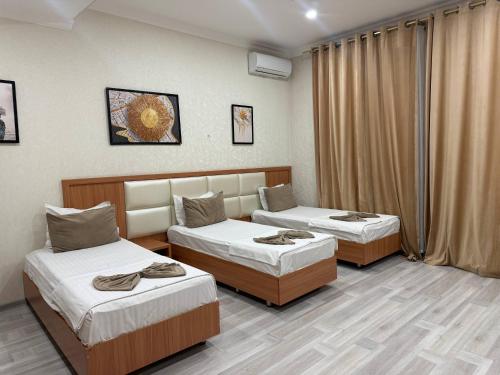 een hotelkamer met 2 bedden en gordijnen bij Hotel Moon in Yakkasaray