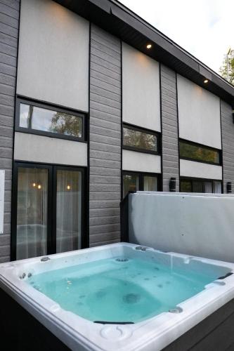 a hot tub in front of a building at Spa - Lake access - Absolute Comfort - L'Herisson in Chertsey