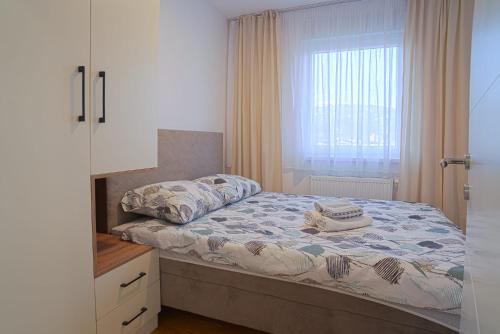 um pequeno quarto com uma cama e uma janela em Hedonist Garden Luxury Apartments em Doboj