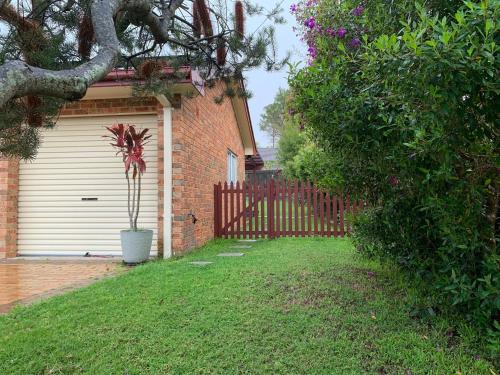 a house with a gate and a potted plant in a yard at Chic Stylish Granny Flat with Stunning Garden View at MC 2079 in Mount Colah