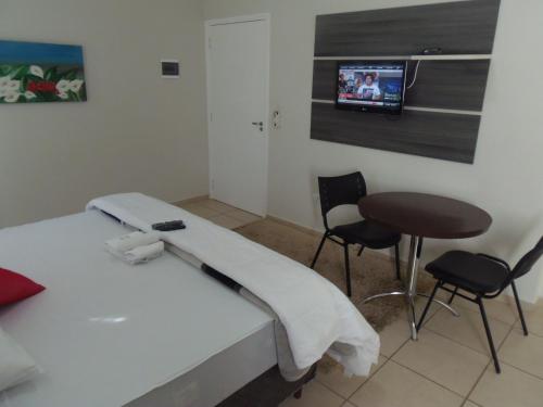 a bedroom with a bed and a table and a tv at Gold - Inn Hotel in Apiaí