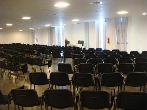 a room filled with chairs and a man standing at a podium at Santa Loja Hotel Residence in Tito