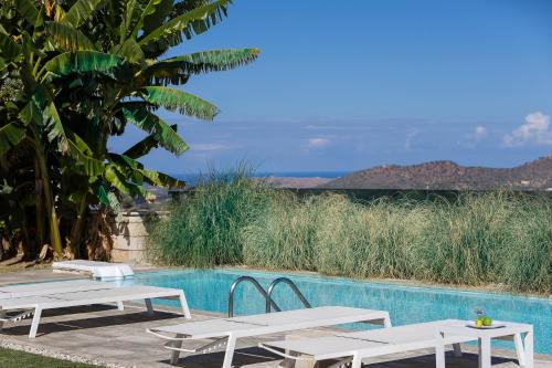 a pool with two white picnic tables next to it at Thalmargia Villas, with Pool, Hot Tub & Ultimate Peace, By ThinkVilla in Garazo