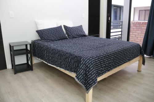 ein Bett mit einer schwarz-weißen Decke und einem Tisch in der Unterkunft Lazarett Loft Modern Apartment in Windhoek