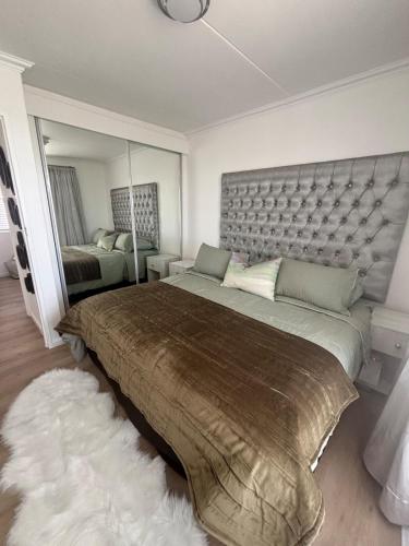 a bedroom with a large bed and a mirror at Stanley's Place at 212 Salerno in Cape Town