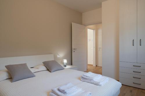 カスティオーネ・デッラ・プレゾラーナにあるBratto Relax Apartmentsのタオルが敷かれた白いベッドのある寝室