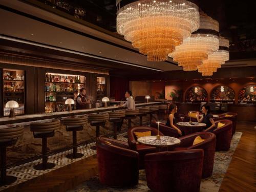Un bar con gente sentada en mesas y candelabros. en Fairmont Singapore, en Singapur