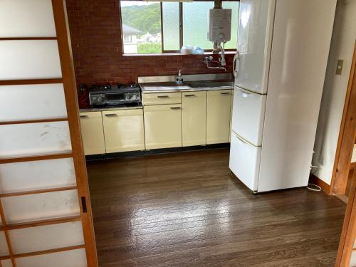 een keuken met een witte koelkast en een spoelbak bij 7Daysあさひや in Matsuzaki