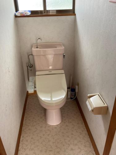 een toilet in een kleine badkamer met een raam bij 7Daysあさひや in Matsuzaki