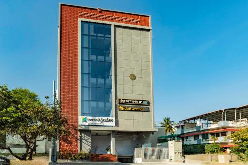 een hoog rood bakstenen gebouw met een bord erop bij Treebo Global Orchid in Mysore