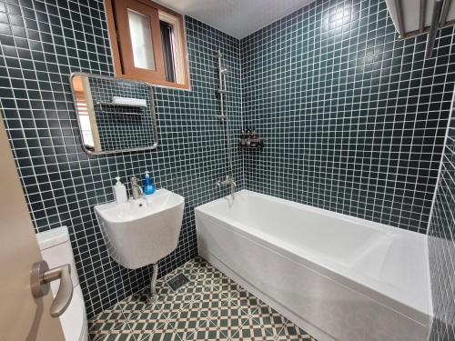 uma casa de banho com paredes em azulejos azuis, uma banheira e um lavatório. em Memories Hotel em Sokcho