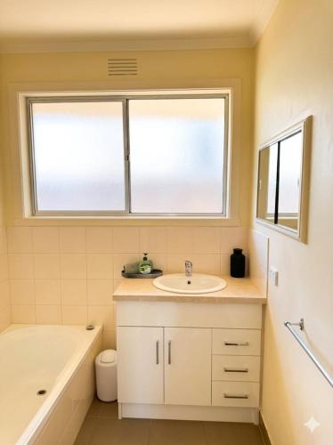 a bathroom with a sink and a tub and a window at The Hamlyn Haven - Sleeps 5 - Central Location in Hamlyn Heights