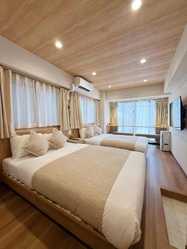 two beds in a large room with windows at Akihabara K in Tokyo