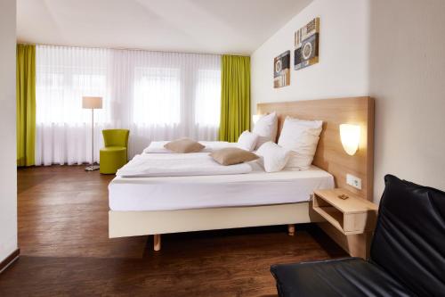 a bedroom with a large white bed and a couch at ante porta DAS STADTHOTEL in Trier