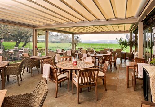 an empty restaurant with tables and chairs and windows at The Welldiggers Arms in Petworth