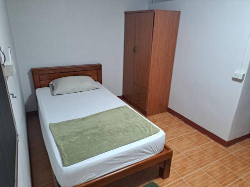 een kleine slaapkamer met een bed en een houten kast bij Casa Scarlet in Bangkok