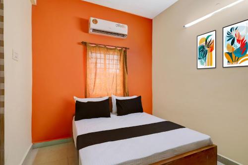 ein Schlafzimmer mit einer orangefarbenen Wand und einem Bett in der Unterkunft Hotel O Rela Hospital Chromepet Formerly Sri Ram Ganesh Residency in Chennai