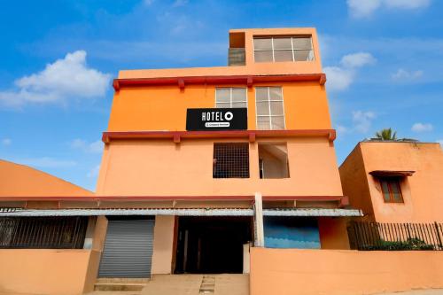 ein hohes orangenes Gebäude mit einem Schild drauf in der Unterkunft Hotel O Rela Hospital Chromepet Formerly Sri Ram Ganesh Residency in Chennai