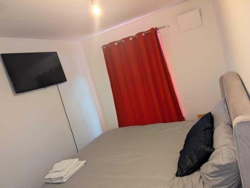 a bedroom with a bed and a red curtain at High class accommodation in Bury