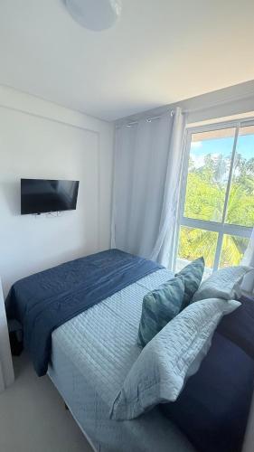 a bedroom with a large bed with a window at Mila rooftop apto 308 in Tamandaré