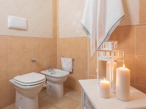 a bathroom with a toilet and a sink and two candles at Premium apartment in Villasimius in Villasimius
