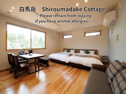 a bedroom with two beds and a table and a couch at Hakuba Highland Hotel in Hakuba