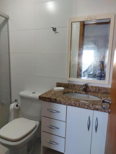 a bathroom with a toilet and a sink and a mirror at Aproveitando o Sol e o Mar de Torres in Torres